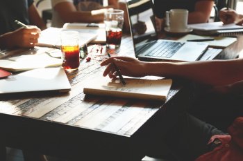 People meet over coffee with notebooks and laptops